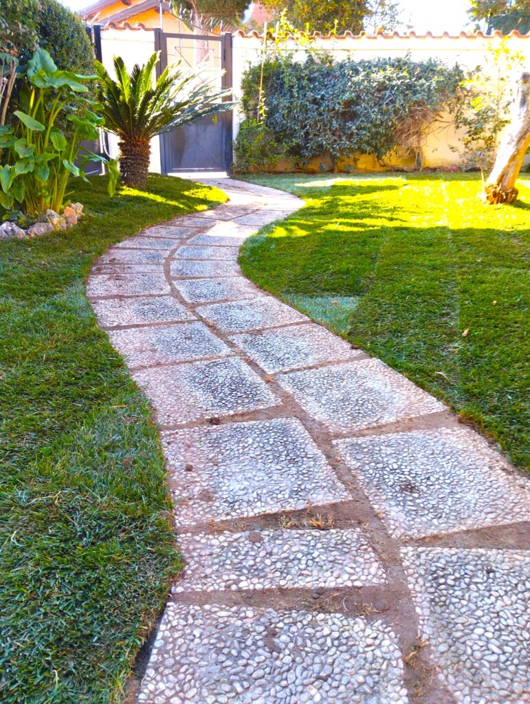 Vialetto lastricato nel giardino circondato da prato verde.